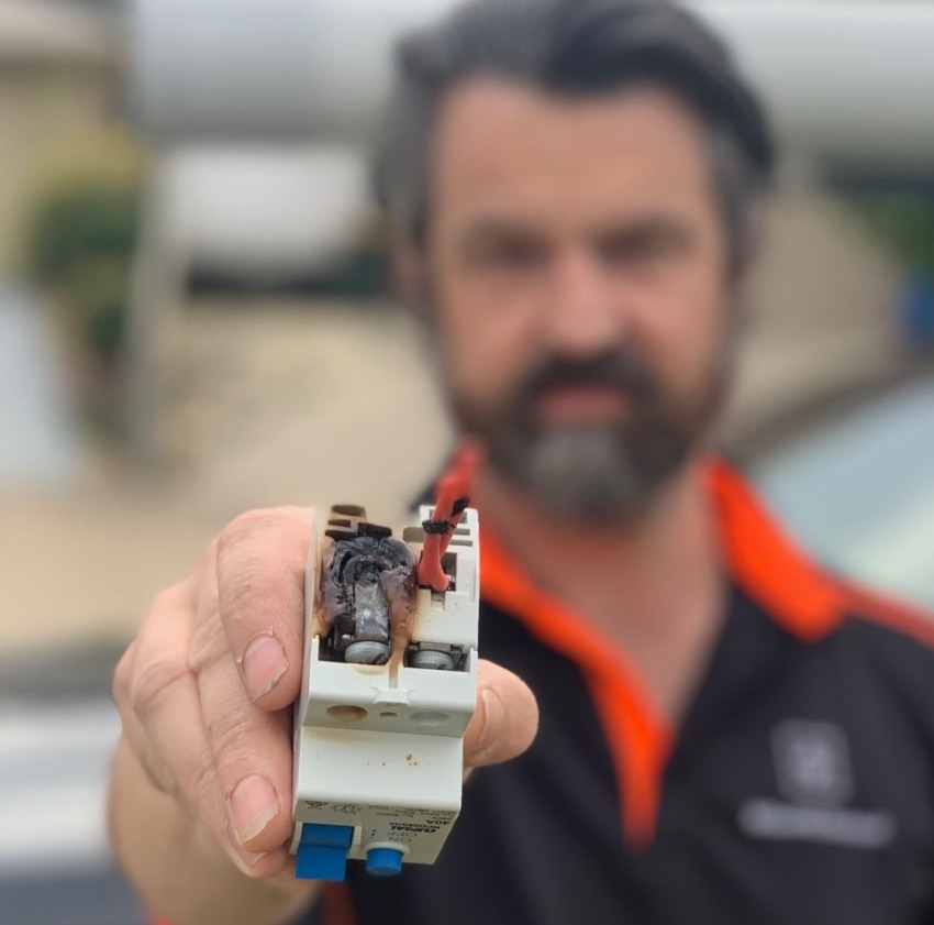Licensed electrician Rhett Andrews holding a burnt-out fuse from a damaged switchboard – Nillumbik Electrical safety inspection in Melbourne.